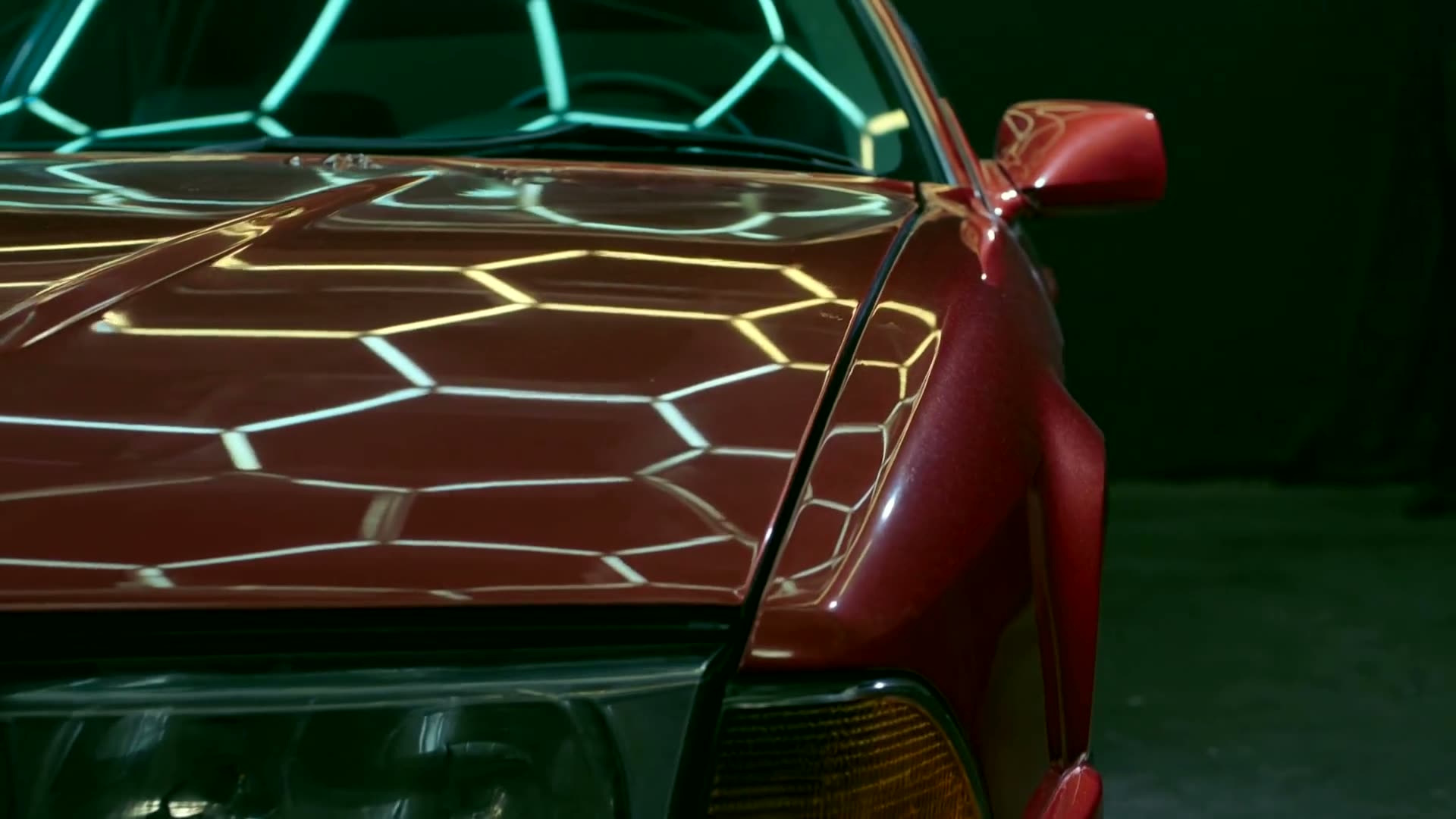 Light travelling across the deep gloss of a candy red sports coupe fender.